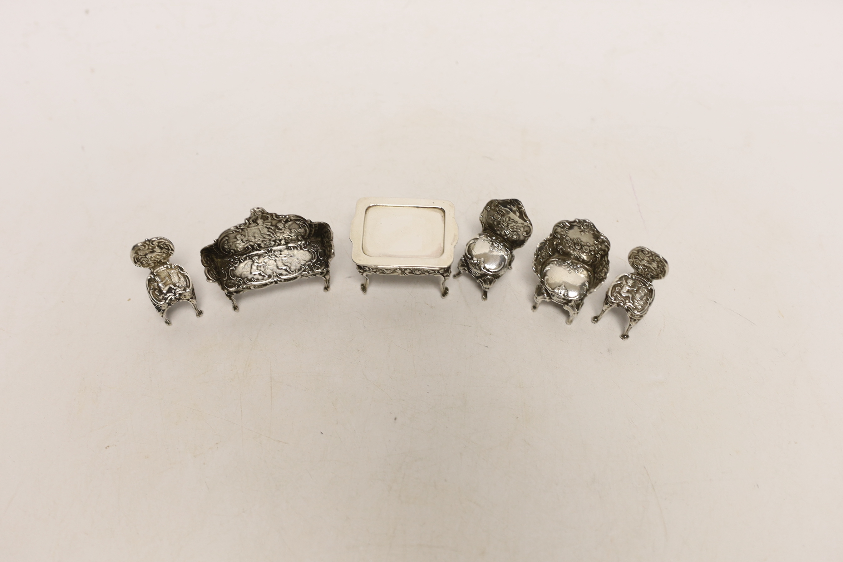 An Edwardian miniature table, 45mm and single chair, by Levi & Salaman, Birmingham, 1902, a later silver single chair, two other white metal miniature chairs and a similar settee.